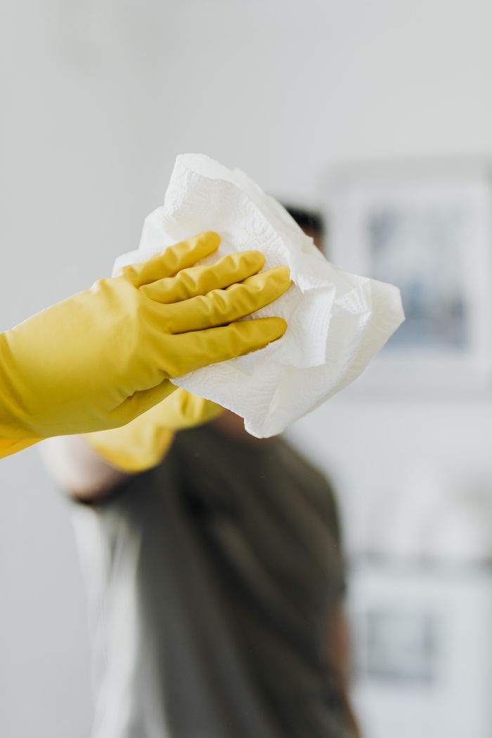 about-04 Anonymous male wearing yellow latex gloves and dark t shirt wiping mirror in bathroom with paper napkin